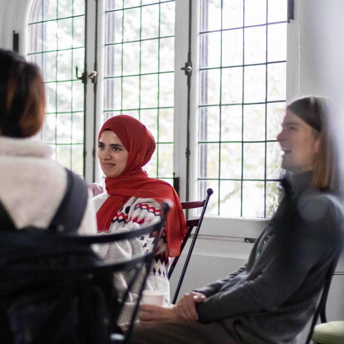 Photo of students seated around a table speaking together